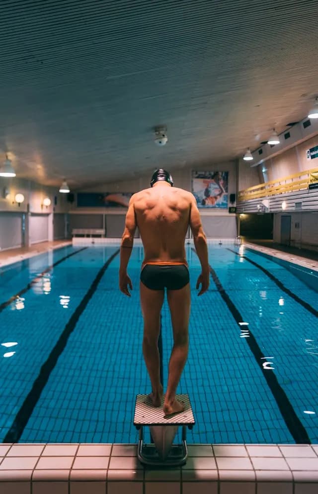 nutotatore visto da dietro mentre sta per entrare in acqua in una piscina